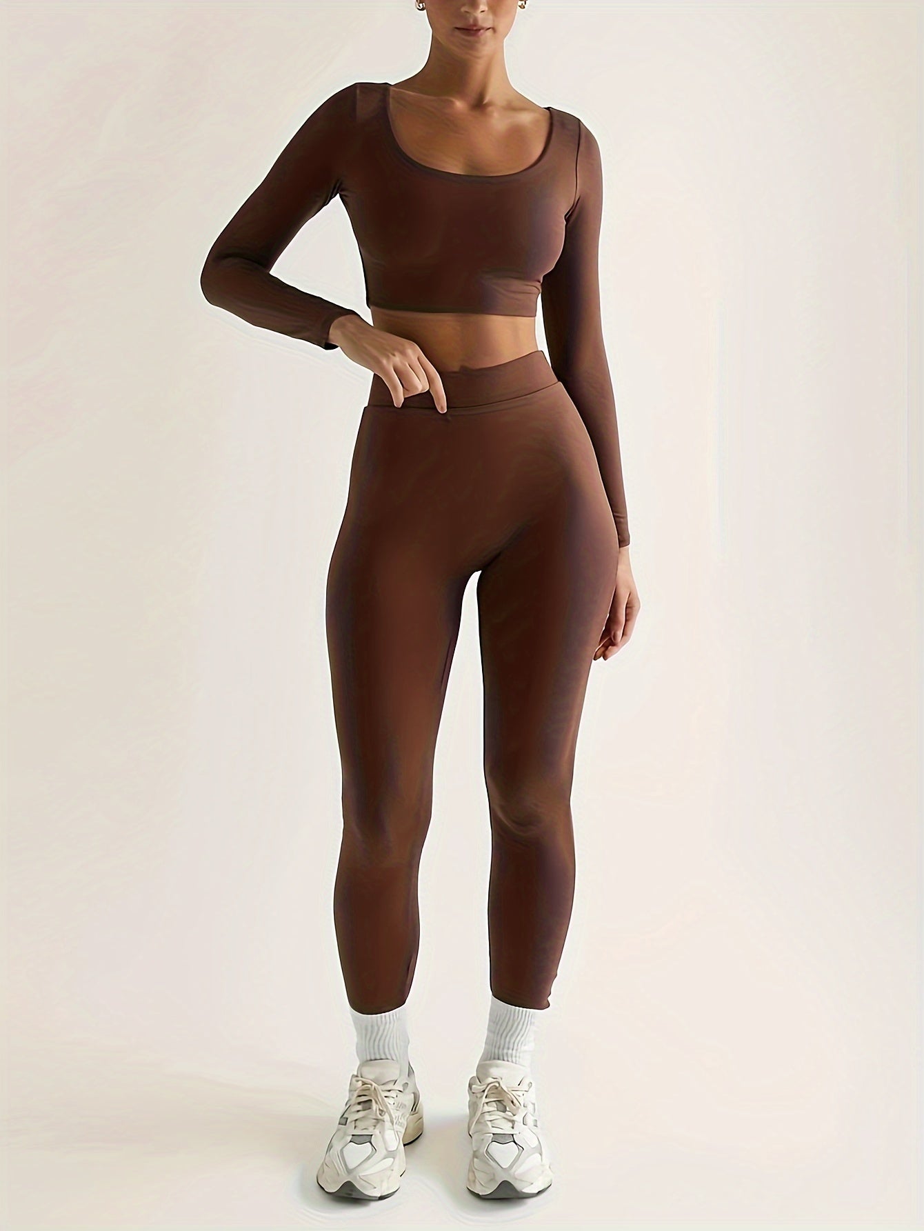 Sportset som bestå r av en lå ngärmad crop top och smala byxor med hög midja