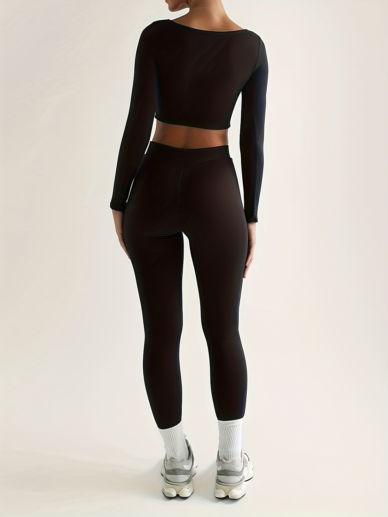 Sportset som bestå r av en lå ngärmad crop top och smala byxor med hög midja