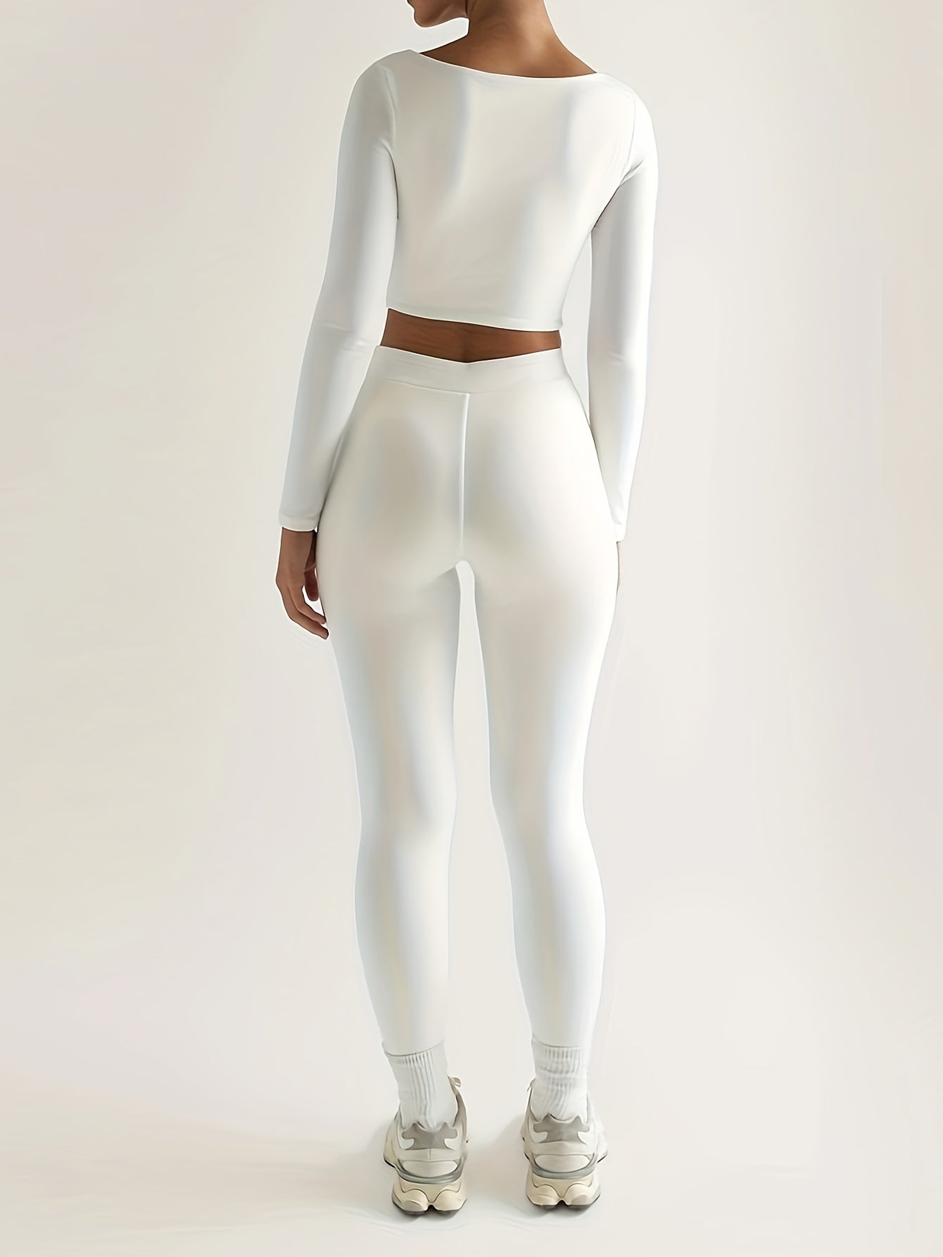 Sportset som bestå r av en lå ngärmad crop top och smala byxor med hög midja