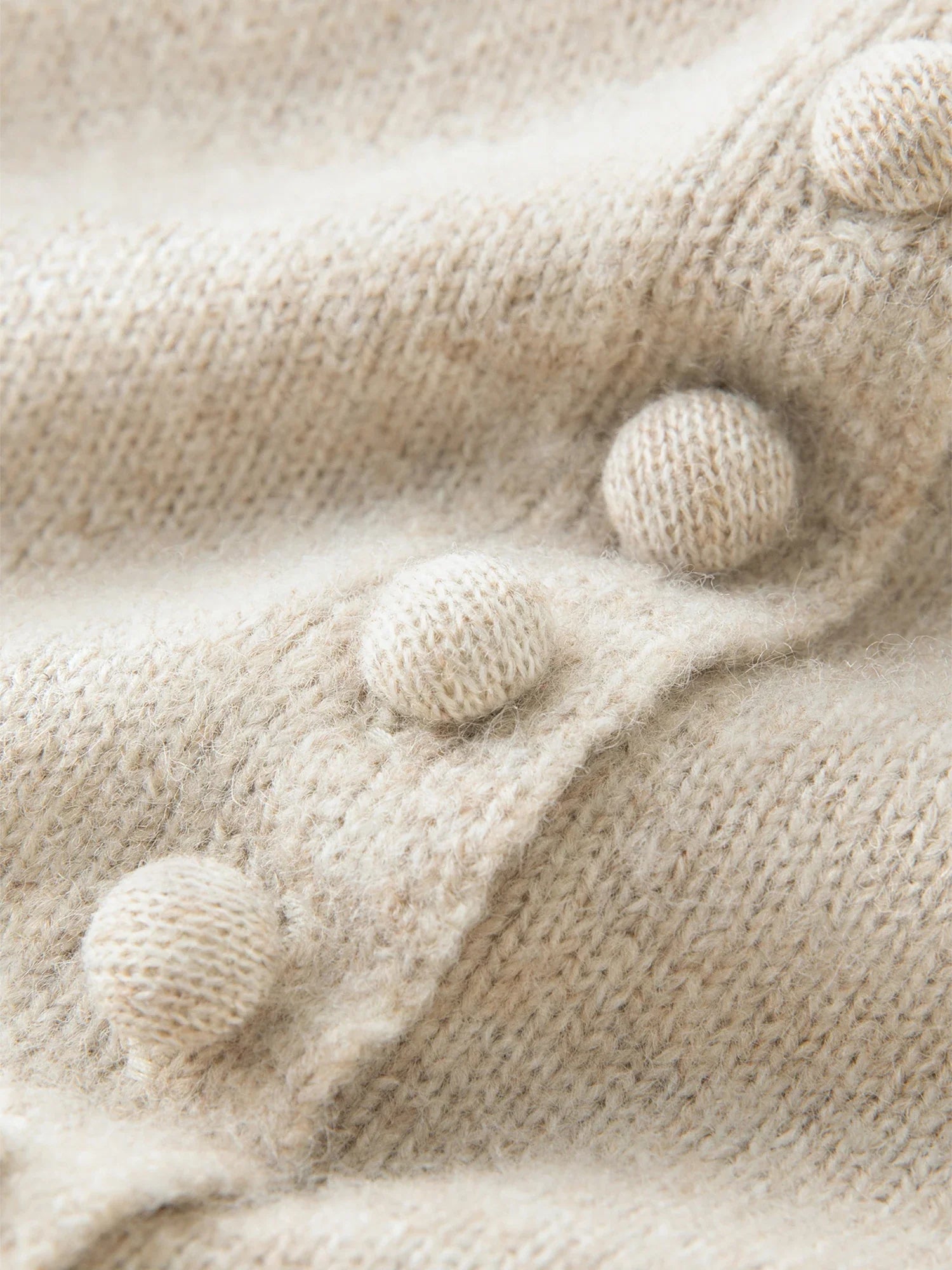 Stickad kofta i blandad stickning med ullknappar