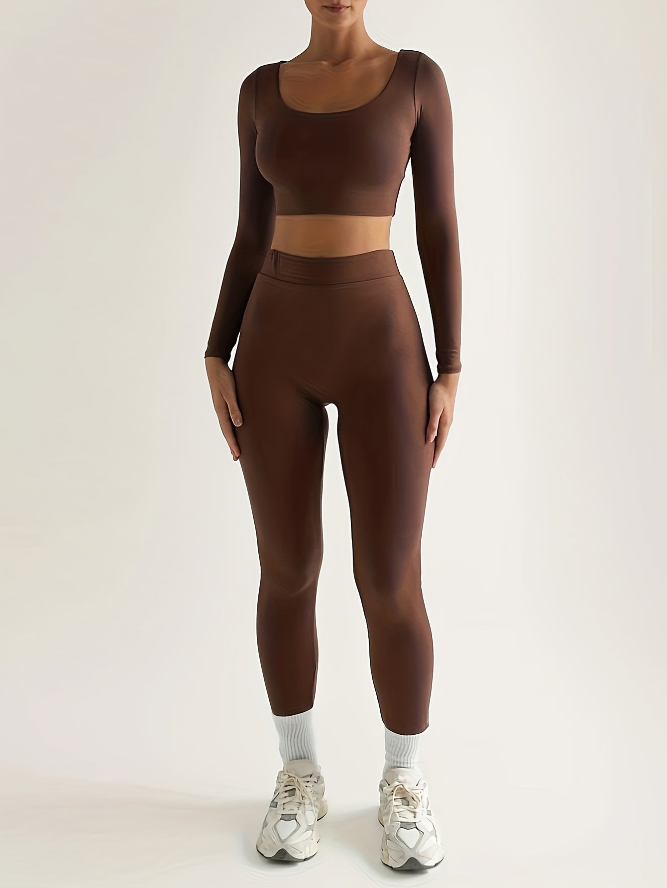 Sportset som bestå r av en lå ngärmad crop top och smala byxor med hög midja